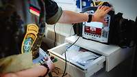 Eine Soldatin bereitet den Defibrillator für den Einsatz vor.