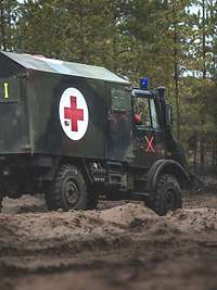 Ein Krankentransportwagen mit Rotem Kreuz auf weißen Grund im Wald