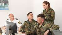 Drei Soldaten und ein Polizist besprechen sich an einem Bürotisch.