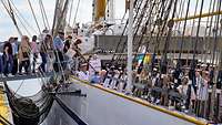 Über die Stelling zwischen einem weißen Schiff und einer Hafenpier gehen viele Menschen Bord des Schiffs.