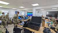 Eine Gruppe von zehn Soldatinnen und Soldaten arbeitet in einem großen Büro gemeinsam.