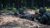Zwei Soldaten liegen parallel zueinander auf dem Boden. Der Soldat im Vordergrund hält ein Maschinengewehr MG5 in der Hand.
