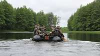 Ein Schlauchboot auf einem See. Mehrere Soldaten paddeln gleichzeitig. 
