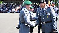 Ein Soldat reicht einem weiteren Soldaten die Hand.