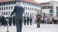 Ein Soldat spielt Dudelsack, im Hintergrund stehen weitere Militärmusiker