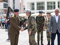 Vier Soldaten und ein weiterer Mann stehen auf einem Platz