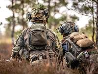 Two soldiers squatting in the forest