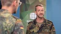 Zwei Soldaten stehen sich bei einem Interview gegenüber