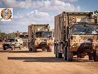 Convoy of military vehicles on a sand road 