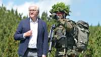 Ein voll ausgerüsteter Soldat erklärt einem Zivilisten mit blauem Jackett etwas.