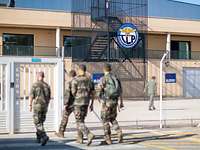 Vier Soldaten bewegen sich auf das Eingangstor zum Trainingsgelände der Air Base zu, das im Hintergrund abgebildet ist. 
