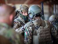Ein deutscher Soldat steht einem italienischen Soldaten gegenüber und legt seine Hand auf dessen Schulter.