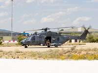 Ein Hubschrauber steht auf der Landebahn. In den offenen Türen sitzen Soldaten. 