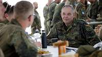 Ein Soldat sitzt mit anderen Soldaten an einem Tisch und unterhält sich.