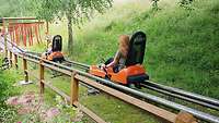 Zwei Kinder mit ihren Schlitten auf der Sommerrodelbahn