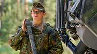 Eine Soldatin steht hinter einem Spürpanzer Fuchs und hält ein schwarzes Probengefäß in den Händen. 