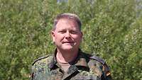 Ein Mann in Uniform lächelt in die Kamera.