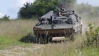 Ein Bergepanzer fährt einen Hang hinab. Zwei Soldaten blicken aus den Luken.