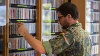 Soldat bei der Durchsicht eines CD-Regals