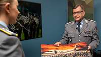 Zwei Soldaten stehen sich beim Interview gegenüber, während ein Soldat ein Bild in den Händen hält.