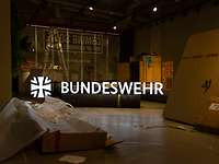 Aufbau der Pop-Up Karrierelounge Blick durch ein Fenster in den halbdunklen Innenraum eines Ladens mit verpackter Ausstattung.
