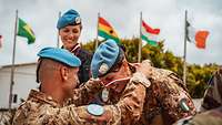 Ein Soldat legt einer italienischen Soldatin eine Medaille um.