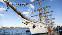 Ein weißes Segelschiff liegt an einer Pier.