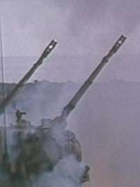 Zwei Flakpanzer vom Typ Gepard schießen im Gelände. Rauch liegt in der Luft.