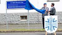 Zwei Männer enthüllen ein Straßenschild für den Exerzierplatz in der Falckenstein-Kaserne in Koblenz