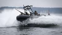 Soldaten in einem Schlauchboot fahren schnell auf einem Gewässer