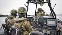 Zwei Soldaten im Fahrstand eines Schlauchbootes fahren auf einem Gewässer