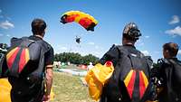 Eine Person im Landeanflug mit einem Fallschirm in Schwarz-Rot-Gold