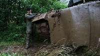 Der Panzerfahrer reinigt einen Teil des Panzers.