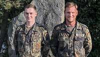 Kompaniechef und Kompanieausbildungsoffizier Zwei Soldaten stehen vor einem Findling nebeneinander und schauen freundlich in die Kamera.