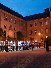 Militärorchester vor einem Schloss bei Abendstimmung