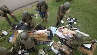 Mehrere Soldaten stehen vor zwei Dummy Puppen mit größeren Verletzungen und behandeln diese.