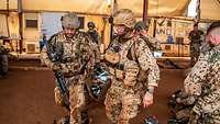 Mehrere Soldaten tragen mit einem Transportsack einen weiteren Soldaten.