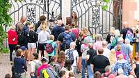 Die ersten Besucher stehen vor dem Tor, das gerade geöffnet wird.