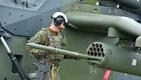 Ein Soldat befüllt den Waffenwerfer eines Hubschraubers mit Raketen.
