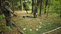 Im Wald ist ein Viereck aus Ästen ausgelegt und darin ein Geländeabschnitt dargestellt.