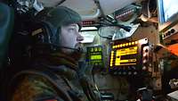 Ein Soldat sitzt vor mehreren Monitoren und hat einen Joystick in der Hand.
