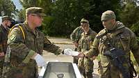 Ein Soldat mit einer gelben Schnur an der Schulter gibt Essen an andere Soldaten aus.