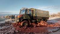 Ein Lkw fährt durch ein zugefrorenes Schlammloch.
