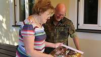 Frau betrachtet gemeinsam mit einem Soldaten eine Bildercollage