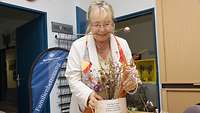 Eine Frau richtet eine Vase mit Trockenblumen her