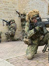 Reservisten üben den Orts- und Häuserkampf Vier Reservedienst Leistende in einer Gasse und mit Waffen im Anschlag