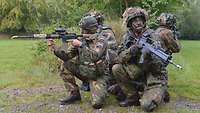 Drei deutsche und ein niederländischer Soldat knieen sternförmig mit ihren Gewehren im Anschlag.
