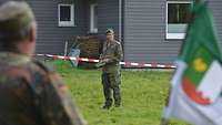 Mit einem Zettel in der Hand steht ein Kommandeur vor seinen Soldaten.