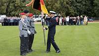 Auf dem Appellplatz hat Flottillenadmiral Ralf Kuchler die Truppenfahne von den Fahnenträgern erhalten