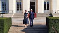 Der Bundespräsident und seine Gattin vor einem Schloss winken zur Begrüßung